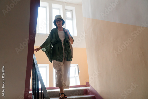 Senior Asian woman walking down the stairs from upper floor inside building photo