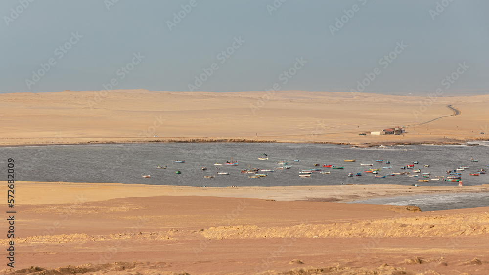 Panorama of a bay with a group of colorful fishermen's boats floating next to the Paracas desert Peru Panorama of a bay with a group of colorful fishermen's boats floating next to the Paracas desert Peru