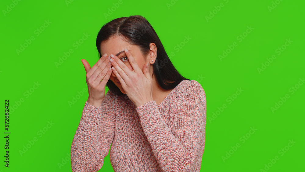 Nosy curious young woman closing eyes with hand and spying through fingers, hiding and peeping, binocular gesture, exploring way, seeking something in distance. Girl isolated on chroma key background Nosy curious young woman closing eyes with hand and spying through fingers, hiding and peeping, binocular gesture, exploring way, seeking something in distance. Girl isolated on chroma key background
