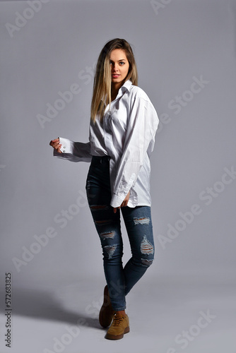 Young woman in the studio, in a white shirt posing on a white background
