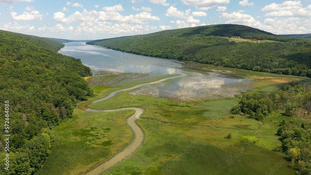 Hemlock Finger Lake peaceful water blue sky with clouds nature outdoors with green mountains and protected wetlands marsh