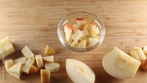 Cutting an apple on a cutting board and putting into the bowl