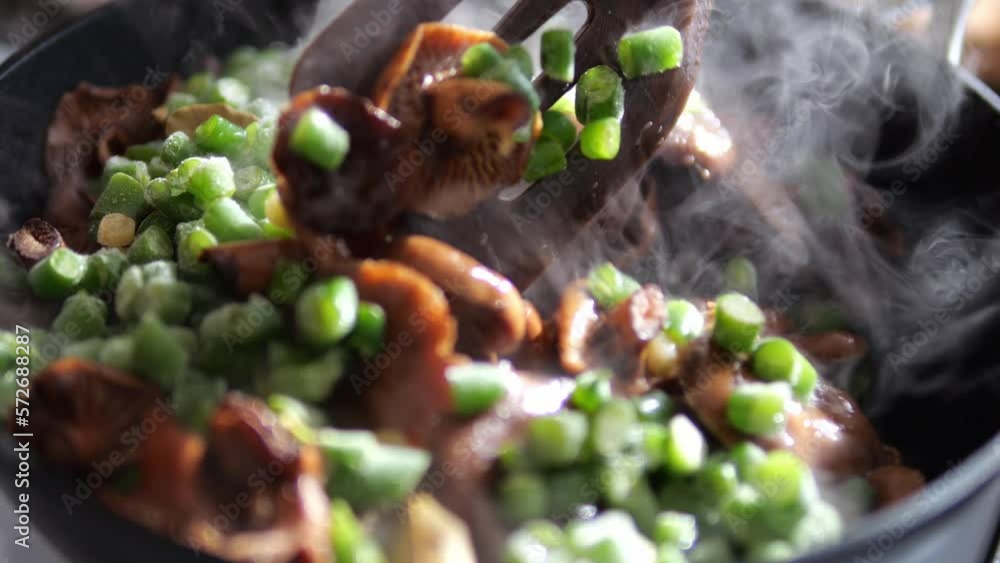 Cooking a dish with mushrooms and asparagus. A delicious dinner is steaming in the pan. Cooking a dish with mushrooms and asparagus. A delicious dinner is steaming in the pan.