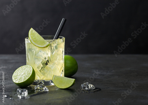 Foto Gimlet Kamikaze cocktail in crystal glass with lime slice and ice on black board