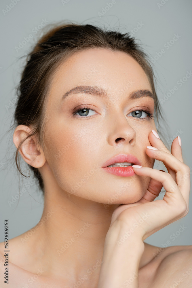 young and pretty woman with natural makeup posing with hand near face isolated on grey. young and pretty woman with natural makeup posing with hand near face isolated on grey.