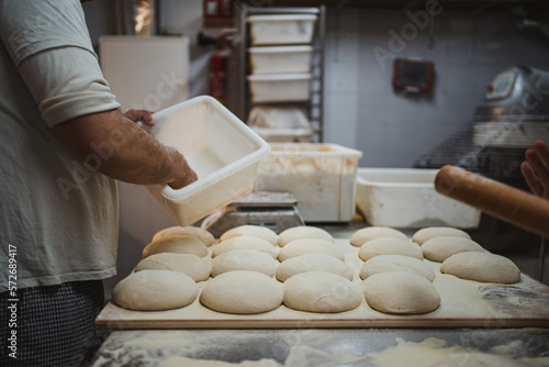 Many preshaped pizza dough balls with flour on it at the kitchen of bakery