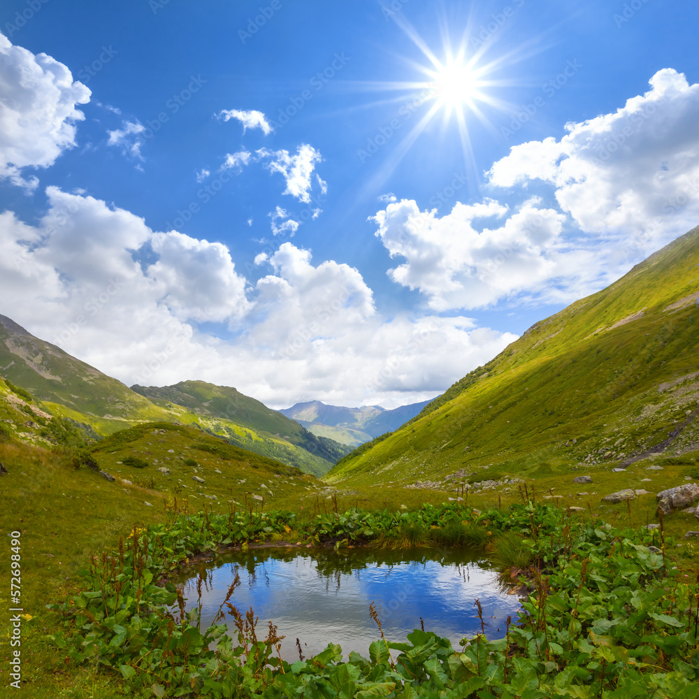 small blue lake in the mountain valley under a sparkle sun