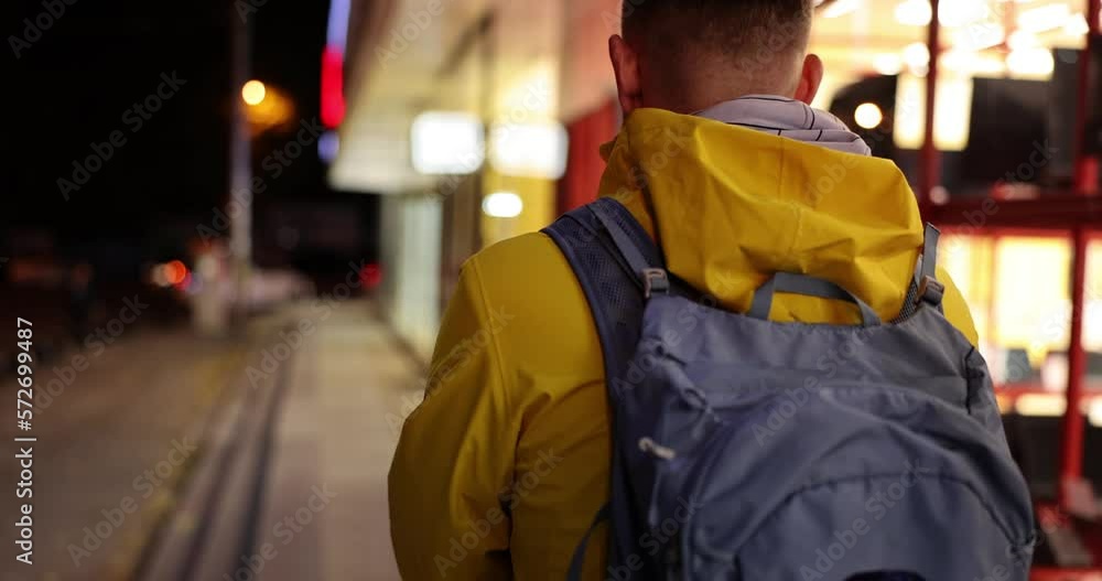 A man with a backpack goes along the evening street, close-up