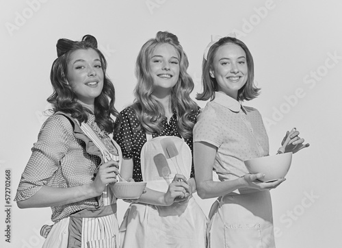 Retro style portrait of beautiful young women, housewives with cooking tools. Black and white image in vintage style photo