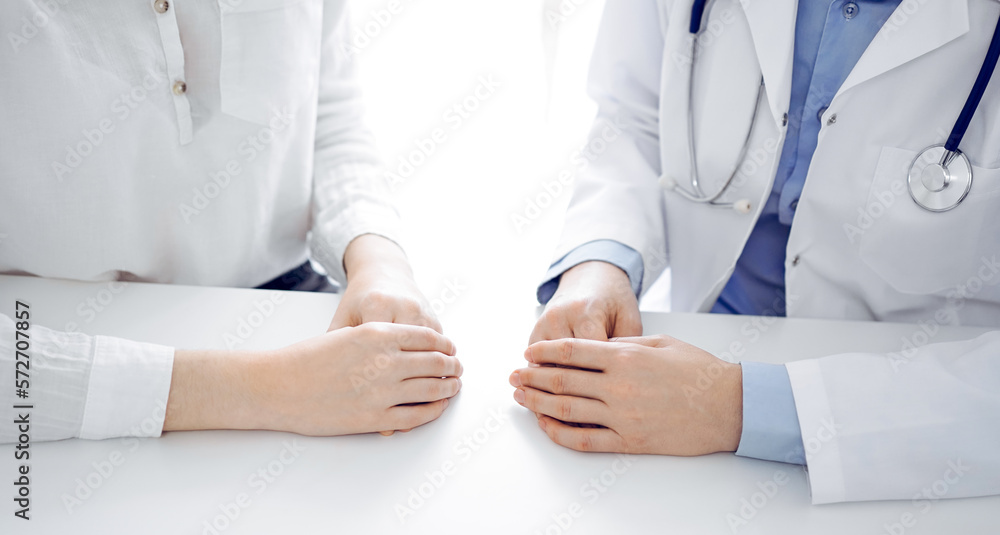 Doctor and patient discussing current health questions while sitting near of each other at the table in clinic, just hands closeup. Medicine concept Doctor and patient discussing current health questions while sitting near of each other at the table in clinic, just hands closeup. Medicine concept