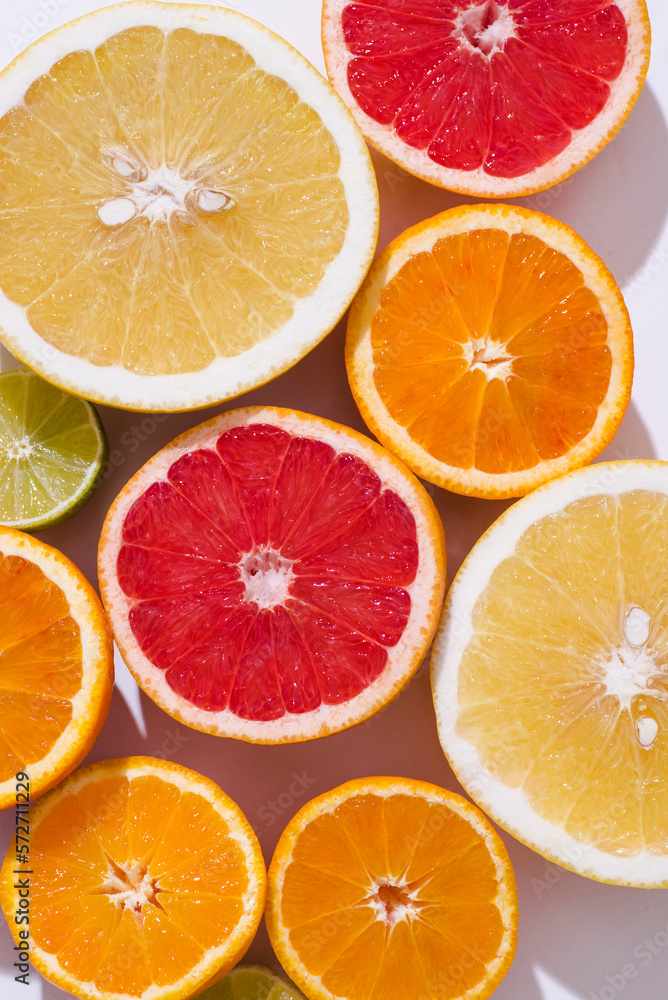 Fresh citrus fruit: oranges, red blood oranges(tarocco), pomelo, lime om the white background , sunlight, top view, close up Fresh citrus fruit: oranges, red blood oranges(tarocco), pomelo, lime om the white background , sunlight, top view, close up