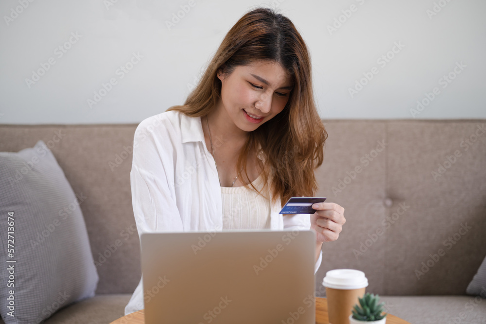 Woman shopping on laptop holding credit card for Internet online e-commerce shopping spending money Online shopping Mobile phone laptop technology concept Woman shopping on laptop holding credit card for Internet online e-commerce shopping spending money Online shopping Mobile phone laptop technology concept