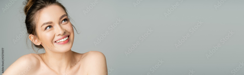 Pretty fair haired woman with naked shoulders looking up isolated on grey, banner. Pretty fair haired woman with naked shoulders looking up isolated on grey, banner.