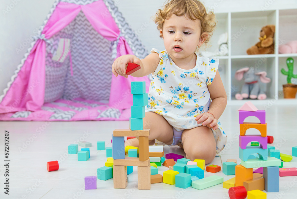 The child plays in the children's room with a wooden constructor. Selective focus. The child plays in the children's room with a wooden constructor. Selective focus.