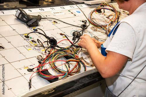 Hands of employees who check the quality of the wiring for cars at a modern plant on a special stand at the production shop