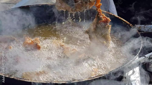 Fish meat fried in oil - grabbing and removing deep fried and dripping cuts of carp from boiling, steaming and bubbling fat with tongs. Healthy food cooking - dietary nutrition rich in omega 3 acids.