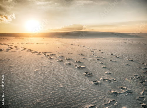 Footsteps footprints on sand dunes in desert at sunset