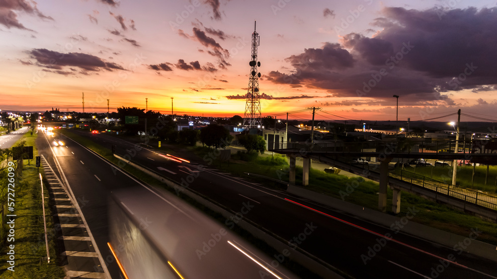 Marilia, Sao Paulo, Brazil, January 26, 2023. traffic on the Highway and silhouette of a telecommunications antenna in Marilia city, during a sunset