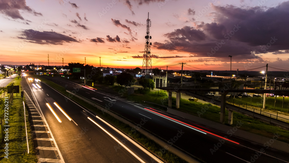 Marilia, Sao Paulo, Brazil, January 26, 2023. traffic on the Highway and silhouette of a telecommunications antenna in Marilia city, during a sunset
