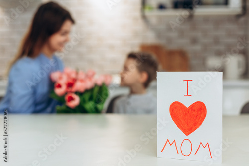 Happy Mother`s day! Small son hugging her mom on kitchen. Happy family concept