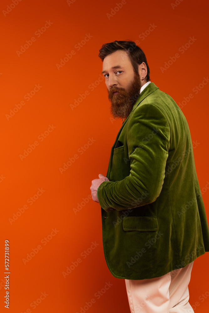 Stylish man in green velvet jacket looking at camera on red background. Stylish man in green velvet jacket looking at camera on red background.