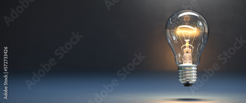 A classic lightbulb hovering over a dark surface, the filament is glowing - concept for having an idea, innovation photo