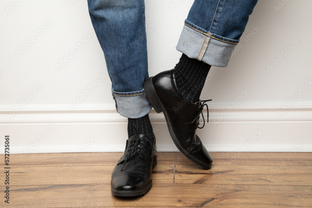 Product photo of men's footwear. This is a close up on a man wearing black leather dress shoes, black dress socks and blue jeans. Product photo of men's footwear. This is a close up on a man wearing black leather dress shoes, black dress socks and blue jeans.