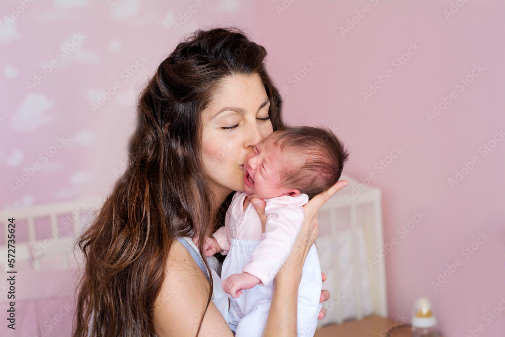Mother hugging and kissing her newborn crying baby Mother hugging and kissing her newborn crying baby