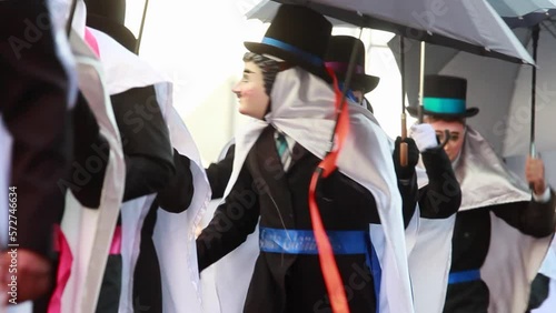 close up group of mexican male dancers during the Carnival in tlaxcala wearing a traditional costume with wooden mask and holding in one hand a black umbrella