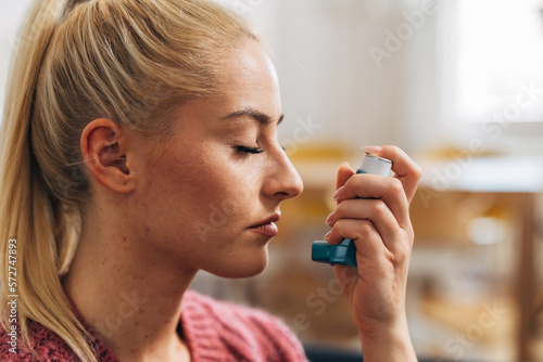 Close up view of a blonde woman with an asthma inhaler photo