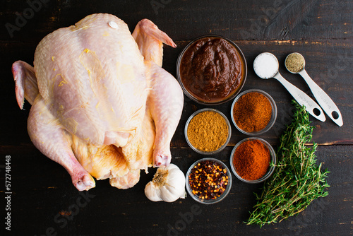 Apple Butter Roasted Chicken Ingredients on a Wooden Table: Raw chicken, apple butter, and spices on a dark wood background