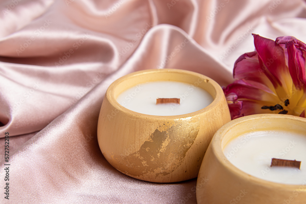 Candles in plaster candlesticks. Candle is decorated with potal closeup. Pink silk fabric Candles in plaster candlesticks. Candle is decorated with potal closeup. Pink silk fabric