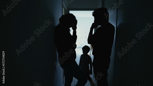Silhouette of couple standing in corridor in crisis. Parents with child feeling worry and anxiety. Husband and wife discussing difficult situation © Marco