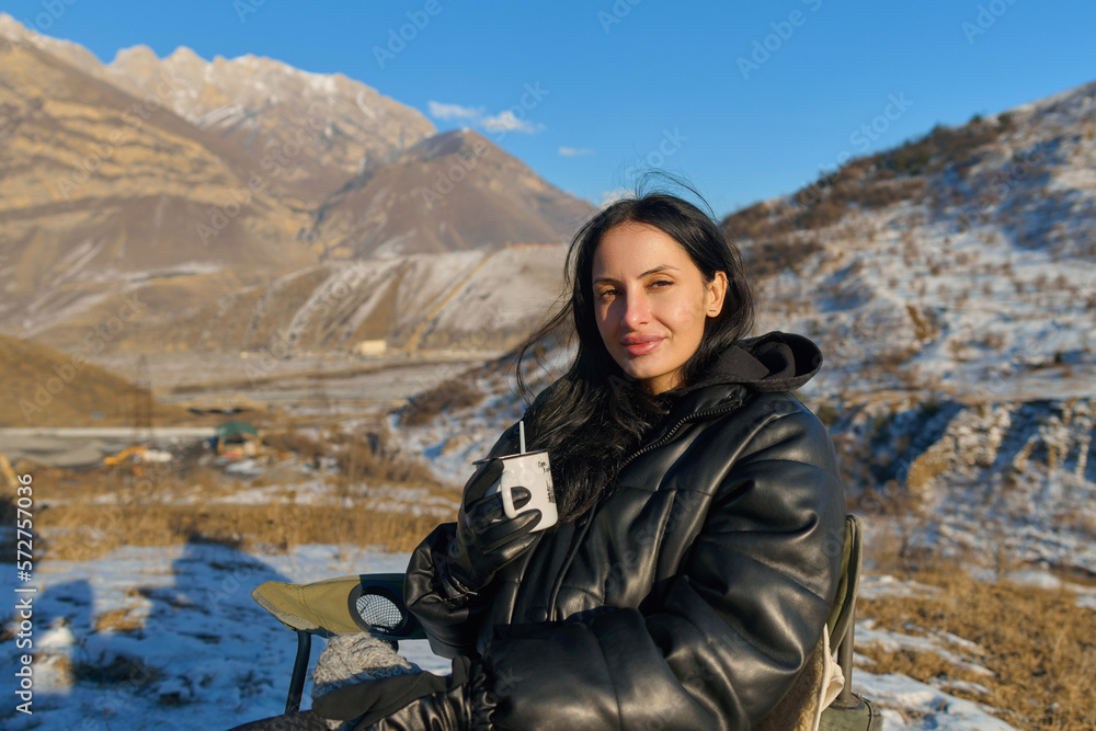 Naklejka premium girl drinks tea in winter in the mountains