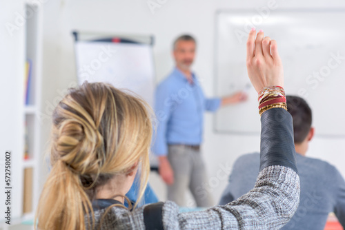 young woman raising hands in class of middle school