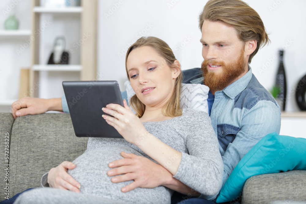 couple pregnant woman and husband looking tablet