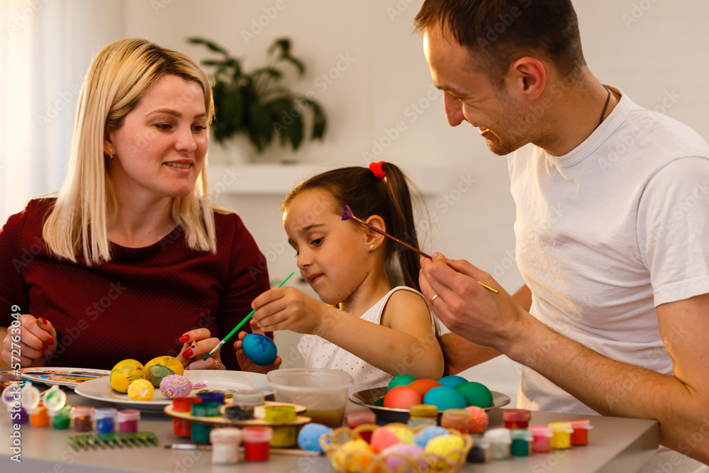 Naklejka premium Easter Family traditions. family paint eggs at kitchen table