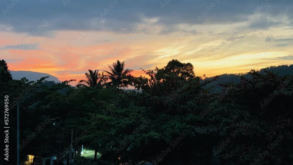sunset overlooking the mountains, palm trees and people walking along the road. sunset overlooking the mountains, palm trees and people walking along the road.