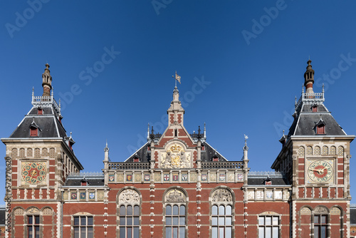 Facade of the Amsterdam Central Station against a blue sky.