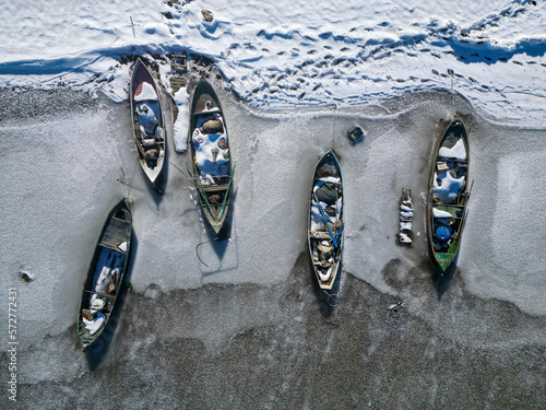 fishing boats await thawing by the frozen lake