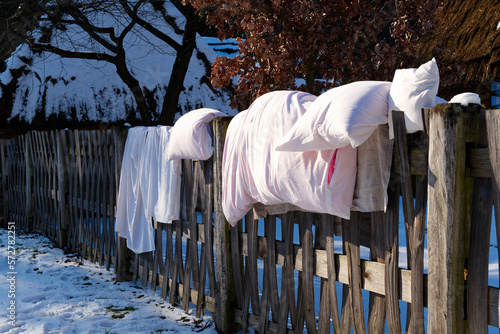 white linen dries on old wooden fence in snow covered country yard in winter