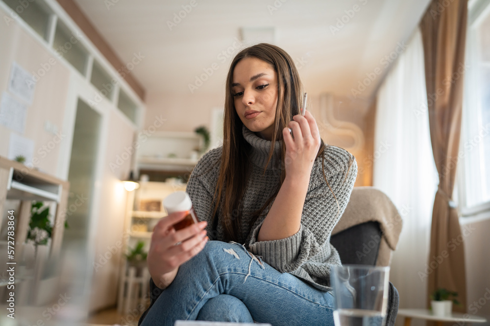 One woman young caucasian female hold medicine drugs pills tablets while siting at home smoke cigarette thinking trying to quit smoking real person copy space One woman young caucasian female hold medicine drugs pills tablets while siting at home smoke cigarette thinking trying to quit smoking real person copy space