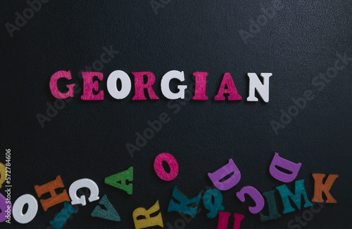 Learning Georgian on blackboard. Concept with text. color wooden letters of the alphabet on a black background