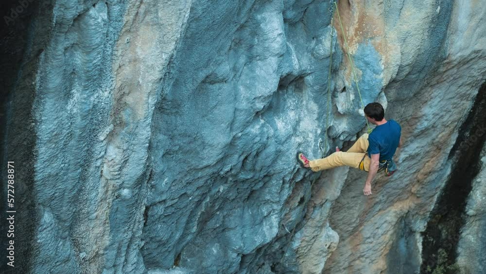 Strong rock climber lead climbing on overhanging rock face, rock climber making a big move, cinematic slow motion rock climbing Strong rock climber lead climbing on overhanging rock face, rock climber making a big move, cinematic slow motion rock climbing