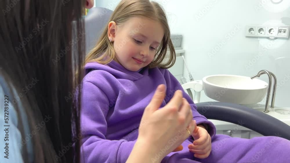 hold the hand, be afraid of the dentist Lovely little kid smiling while talking with the pediatric dentist after doing a tenth examination in a pediatric stomatology cute little girl sits dental chair hold the hand, be afraid of the dentist Lovely little kid smiling while talking with the pediatric dentist after doing a tenth examination in a pediatric stomatology cute little girl sits dental chair