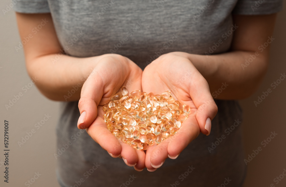 Woman hands hold handful of Vitamin D3 softgels, healthy supplements, concept of wellness, selective focus close up shot Woman hands hold handful of Vitamin D3 softgels, healthy supplements, concept of wellness, selective focus close up shot