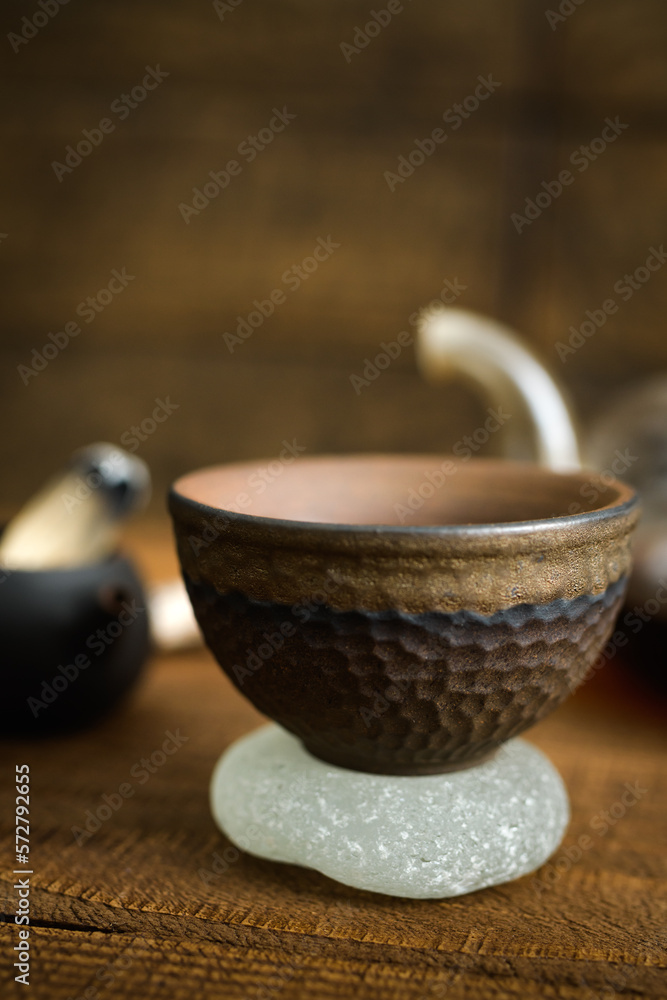 Close up view of chinese ceramic tea bowl on stone on wooden surface Close up view of chinese ceramic tea bowl on stone on wooden surface