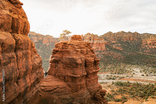 Woman hiker standing on Bell Rock trail in red rock formations within coconino national forest in Sedona Arizona USA against white cloud background.