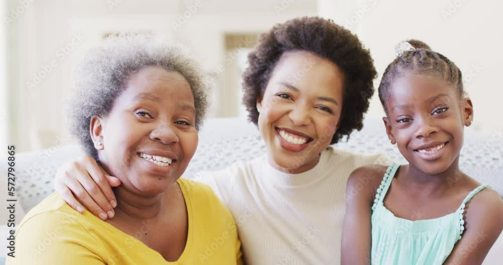 Portrait of smiling african american mother, daughter and grandmother embracing at home, slow motion Portrait of smiling african american mother, daughter and grandmother embracing at home, slow motion