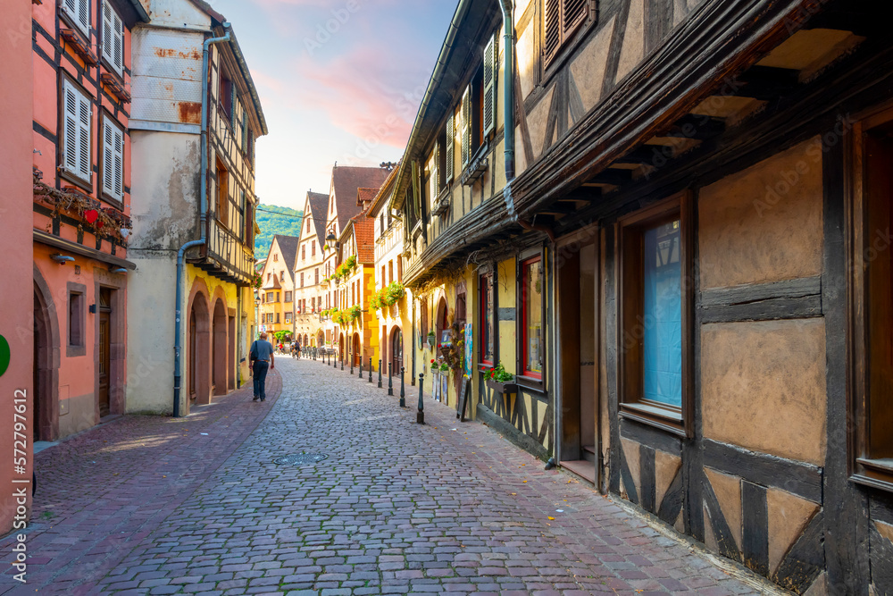 A narrow alley of half timber medieval buildings full of shops, cafes and homes in the Alsatian village of Kaysersberg Vignoble, France.